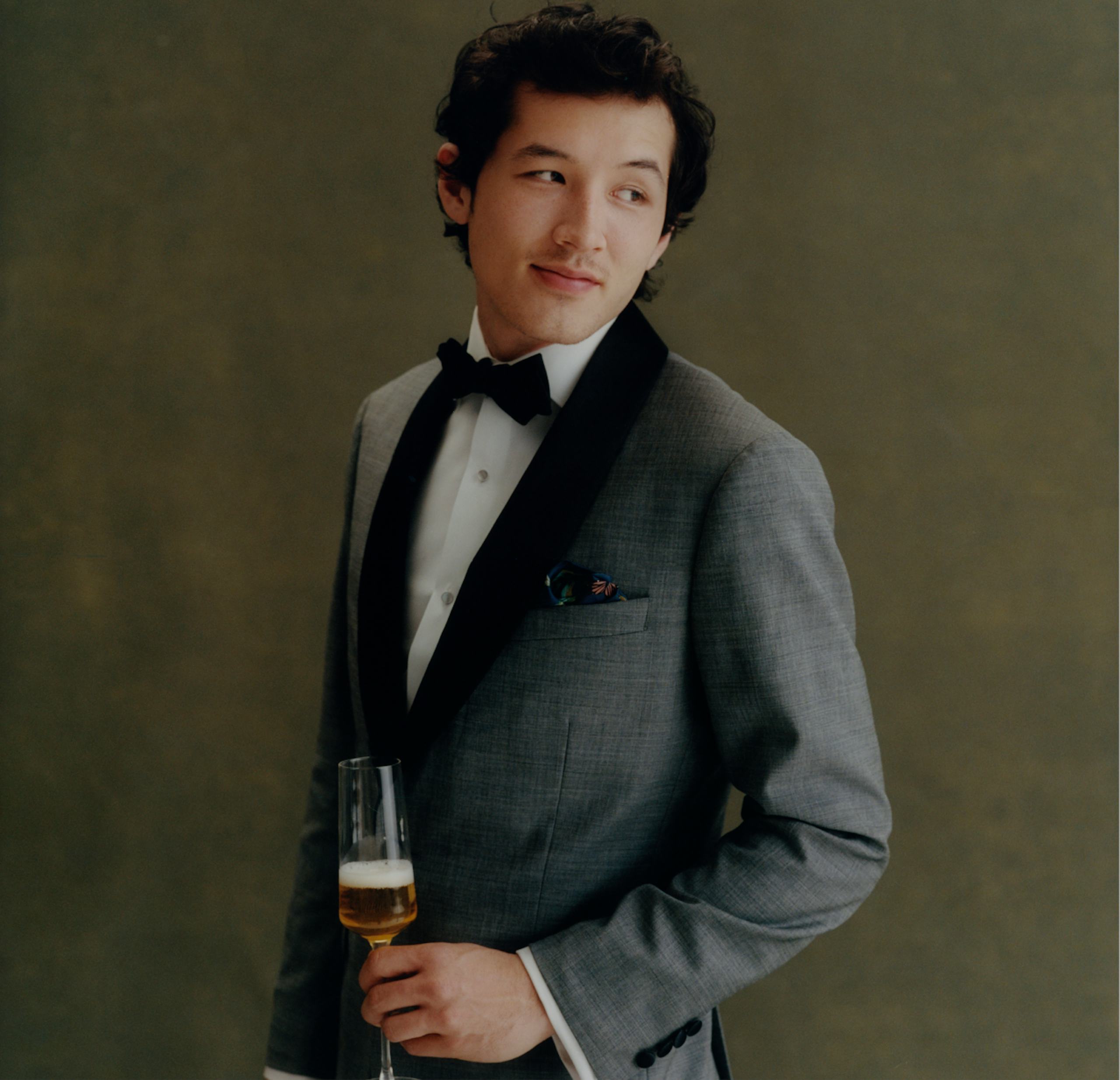 image of model wearing an empire tux and raising a champagne flute