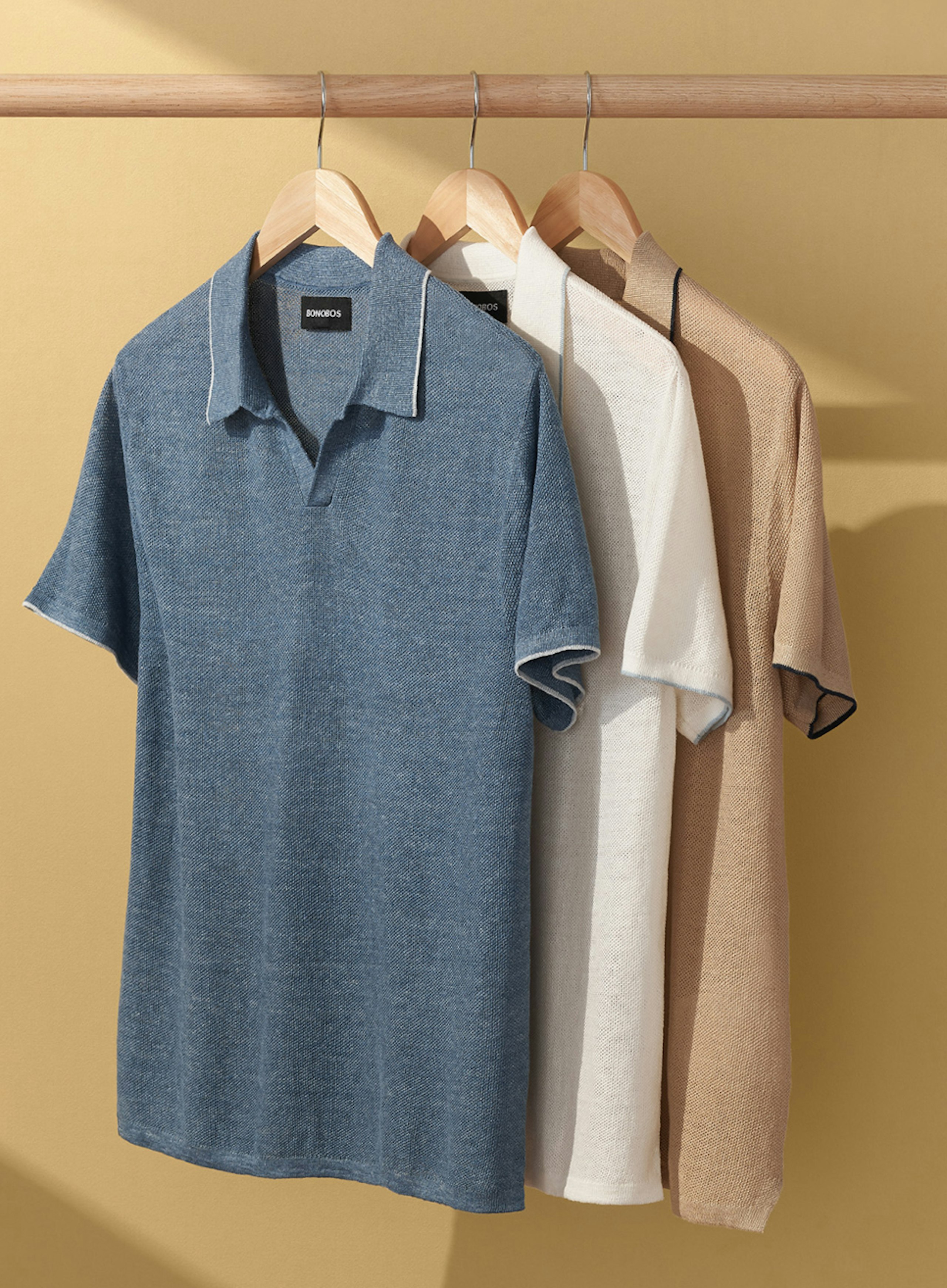 3 polo shirts hanging on a wooden rod 