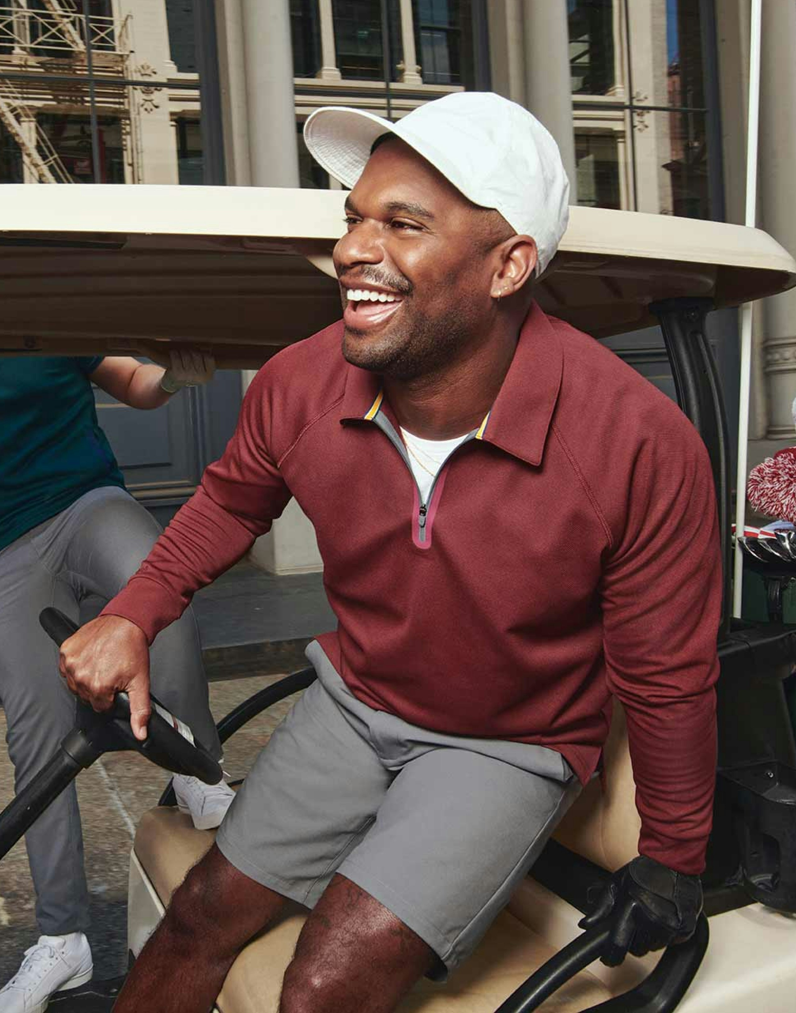Golf Player smiling getting out of a golf cart with a hand on the wheel. 
