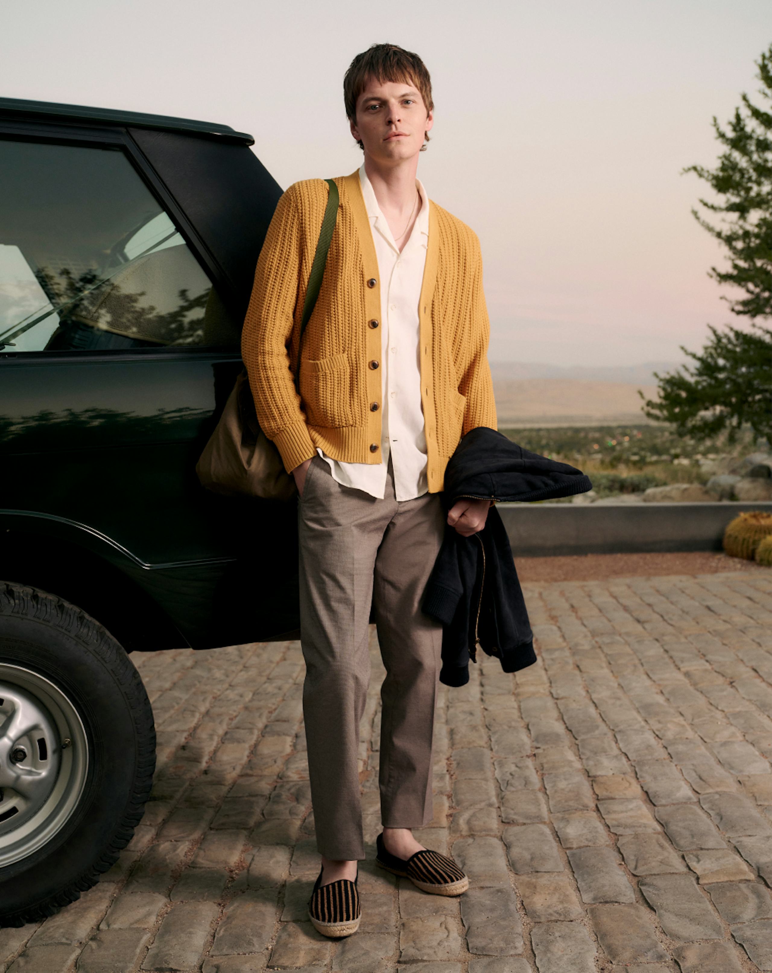 Model wearing Stretch Weekday Warriors, white button up shirt, and cardigan 