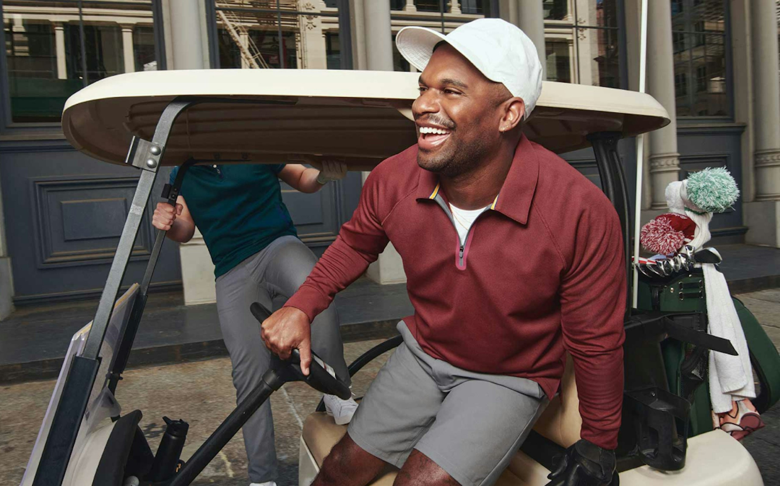 Golf Player smiling getting out of a golf cart with a hand on the wheel. 